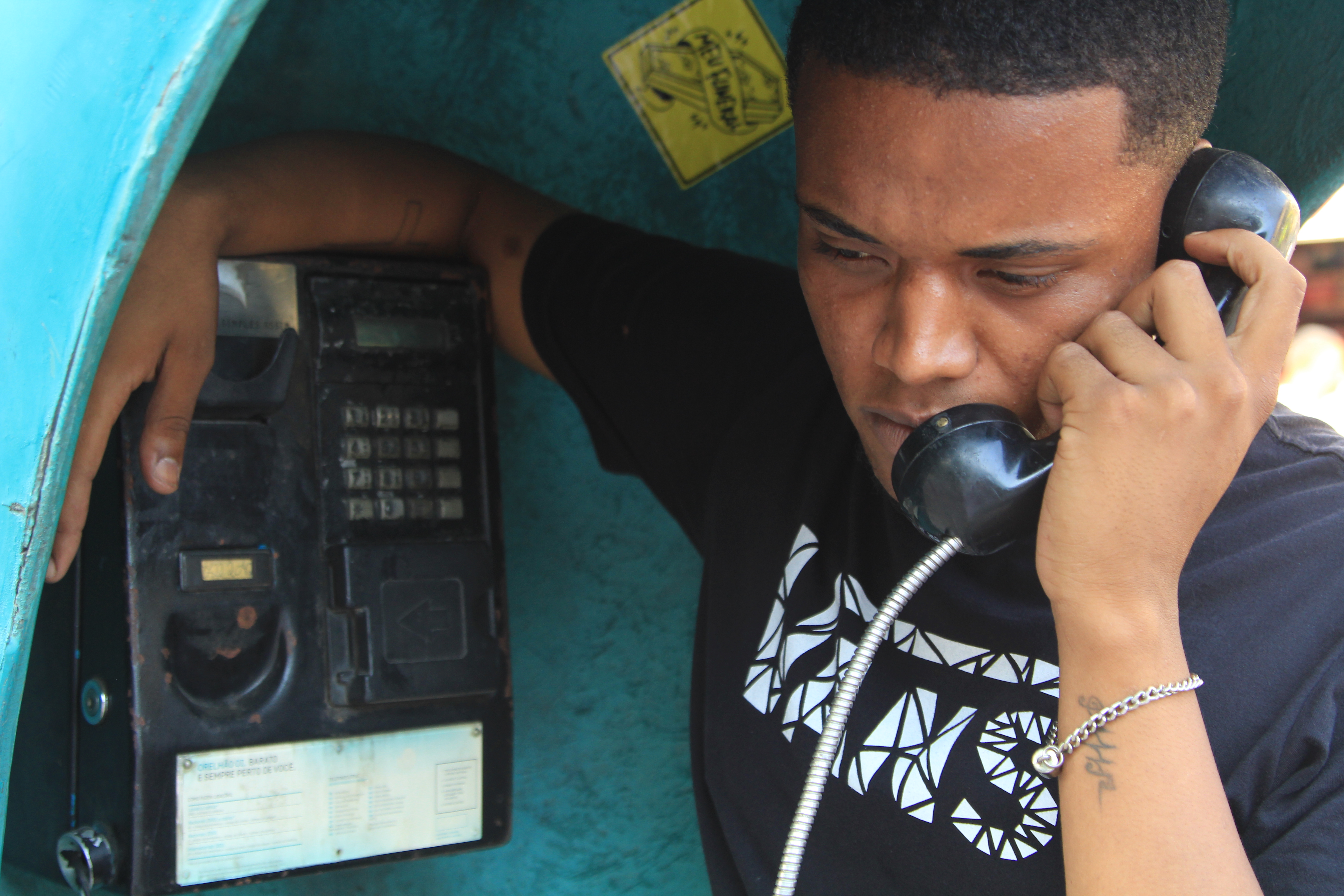 Jovem Negro no orelhão telefone público campanha emprego QUalPerfil# racismo